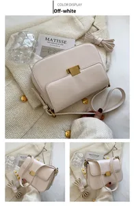 Detail view of off-white leather crossbody bag with golden metal clasp and strap