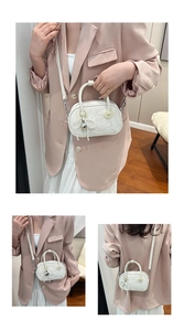 Detailed view of marble pattern handbag featuring pearl heart charm and shoulder strap