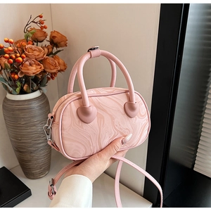 Detailed view of pink marble pattern handbag with heart-shaped accents and strap