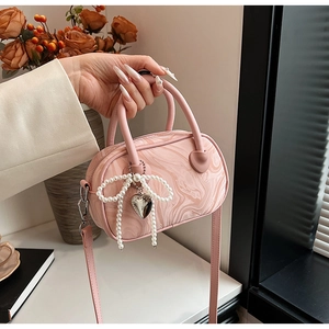 Detail of pink marble pattern handbag with pearl bow and silver heart pendant