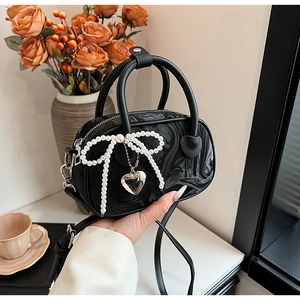 Detail of black marble textured mini bag featuring pearl bow and silver heart charm