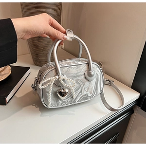 Detail of silver marble velvet handbag featuring pearl bow charm and heart metal hardware