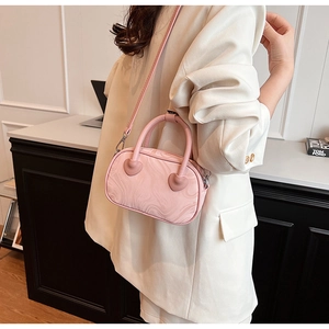 Pale pink marbled velvet handbag with 3D hearts worn crossbody over a beige blazer