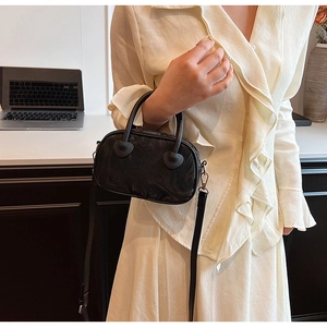 Detail of black marble pattern handbag with heart-shaped metal handle accents and strap