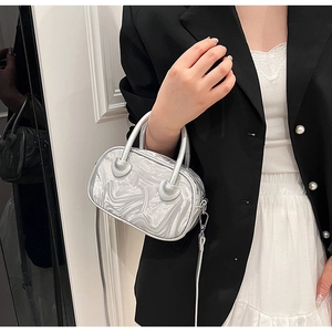 Detail of silver metallic cylinder bag showing high-gloss marble texture and handle