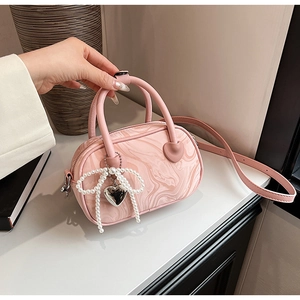 Macro shot of pink marble texture handbag with pearl bow and golden heart charm