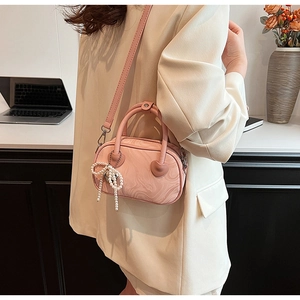 Detailed view of pink velvet bag with marble texture and pearl bow charm accessory