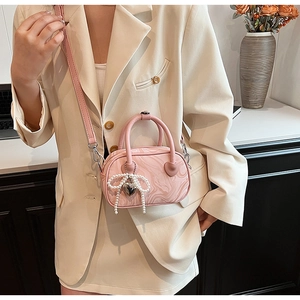 Close-up of pink velvet marble handbag with pearl bow and silver heart charm