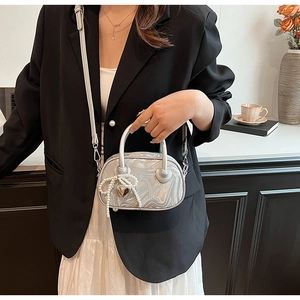 Detail of silver mini crossbody bag with pearl bow charm and heart metal buckle accessory