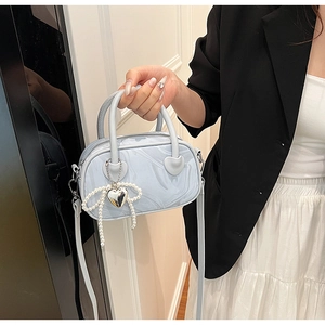 Detail of light blue marble-pattern handbag with pearl bow and silver heart pendant
