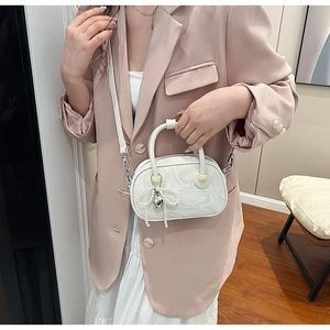 Close-up of a white marble-patterned velvet handbag featuring a pearl bow and heart charm
