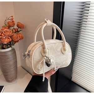 Detail of marble pattern velvet handbag with pearl heart charm and round handles