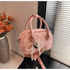 Pink marble pattern Boston handbag with pearl bow and heart charms in a lifestyle setting