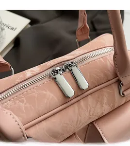 Detail of smooth silver double zippers and marble texture on a pink PU leather handbag