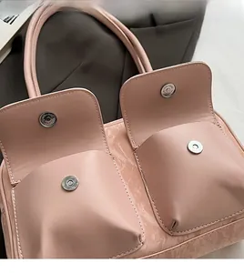 Detailed macro view of light pink PU bag with dual front pockets and silver magnetic buckles