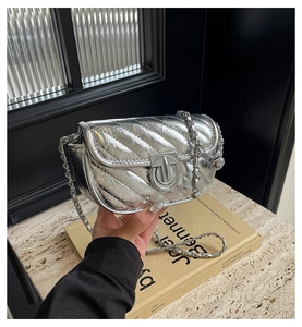 Detail of silver metallic quilted crossbody bag with stylish round metal clasp and chain
