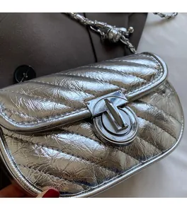Detail of silver metallic quilted handbag with twist-lock and textured chain strap