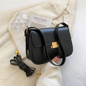 Chic black faux leather crossbody bag with gold buckle on elegant tweed texture
