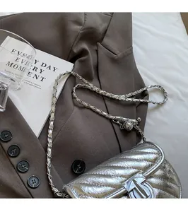 Detailed view of silver quilted crossbody bag with metal TB clasp and chain strap
