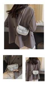Detail of silver quilted chain bag featuring round metal lock and textured surface