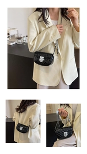 Detail view of a black quilted chain crossbody bag with silver twist lock and metal strap