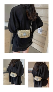 Close-up of golden quilted bag with V-shaped stitching and metallic chain strap detail