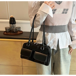 Detail of black PU leather shoulder bag with front flap pockets and dual handles