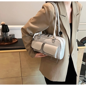 Close-up of beige PU leather shoulder bag with dual front pockets on a model