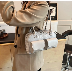 Detail of grey shoulder bag with double front pockets and glossy pleated texture finish