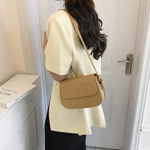 Zijaanzicht van een minimalistische kaki kunstlederen crossbodytas gedragen door model
