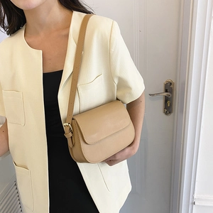 Gedetailleerde weergave van een beige zadeltas met verstelbare riem en goud metaal