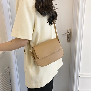 Detail van lichtbruine lederen crossbodytas met gouden gesp op een schouderband