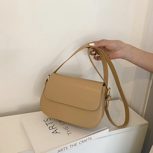 Detail van de beige vierkante leren tas met matte textuur en gouden metalen gespen