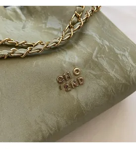 Close-up of pleated grey-green leather texture with gold CH O'2ND metal logo detail