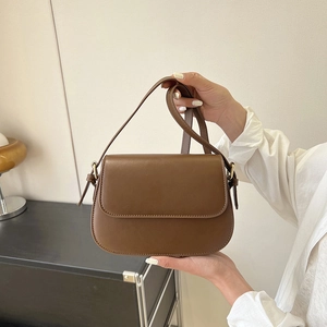 Detail van bruine kunstlederen tas met verstelbare riem en goudkleurige metalen sluiting