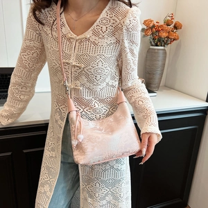 Detail of pink jacquard crossbody bag featuring traditional landscape pattern and bead charms