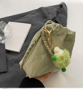 Detail of light green bucket bag with cloud texture, gold chain and plush monster charm