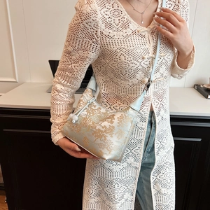 Detail of light blue Chinese style jacquard crossbody bag worn on female model shoulder