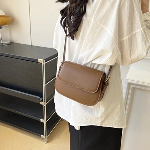 Detail van vintage bruine matte lederen crossbody tas met goudkleurige metalen gesp sluiting