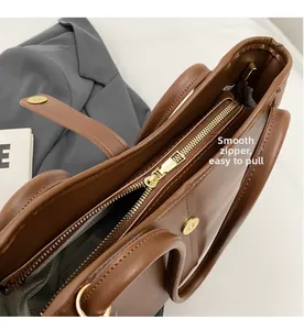 Detail of smooth gold zipper and grey twill lining on a brown leather tote bag