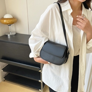Minimalistische zwarte lederen crossbody tas gestyled met een wit shirt en een broek
