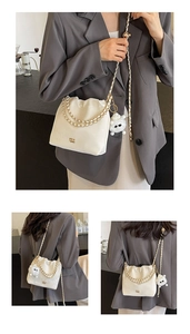 Detail of cream bucket bag with chain strap and cute plush lamb charm on a stylish model