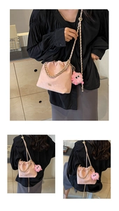 Detailed shot of pink bucket bag with golden chain and cute monster plush pendant