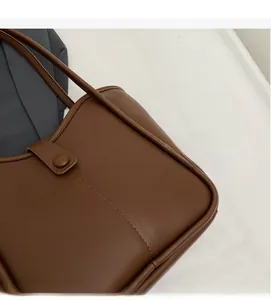 Close-up of a dark brown matte leather bucket bag showing fine stitching and strap details