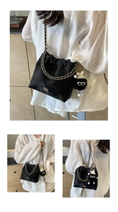 Detail of black velvet drawstring bucket bag with gold chain strap and plush charm
