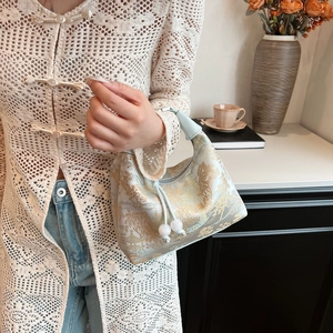 Detailed texture of Chinese style satin dumpling bag with gold landscape embroidery