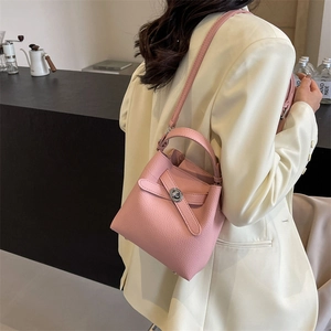 Rosa Eimer-Handtasche mit Litschi-Maserung und silbernem Drehverschluss am Modell
