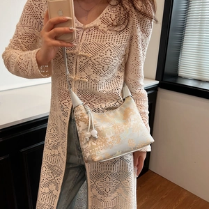 Detail of crossbody dumpling bag with traditional Chinese landscape print and tassel ball