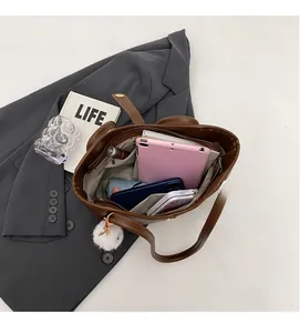 Top view of large brown leather bucket bag interior with compartments and lifestyle items