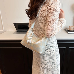 Detail of light blue embroidered hobo bag showing traditional floral patterns and silver buckles
